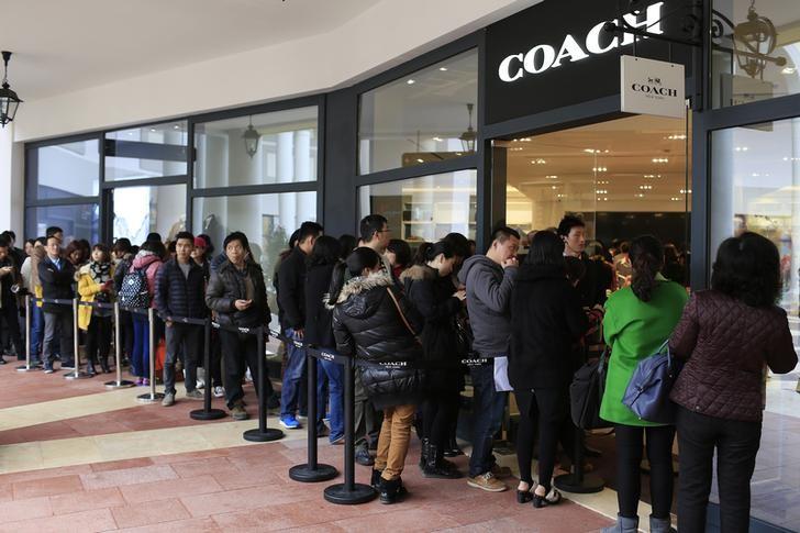 Consumers line up as they wait to go inside a Coach shop in Shanghai