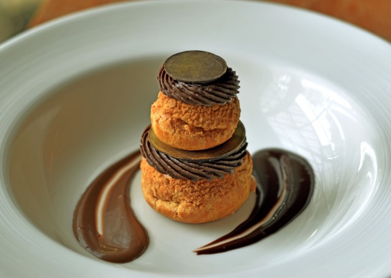 Sable encrusted profiterole with caramel and chocolate Chantilly filling with a marzipan and chocolate disc 